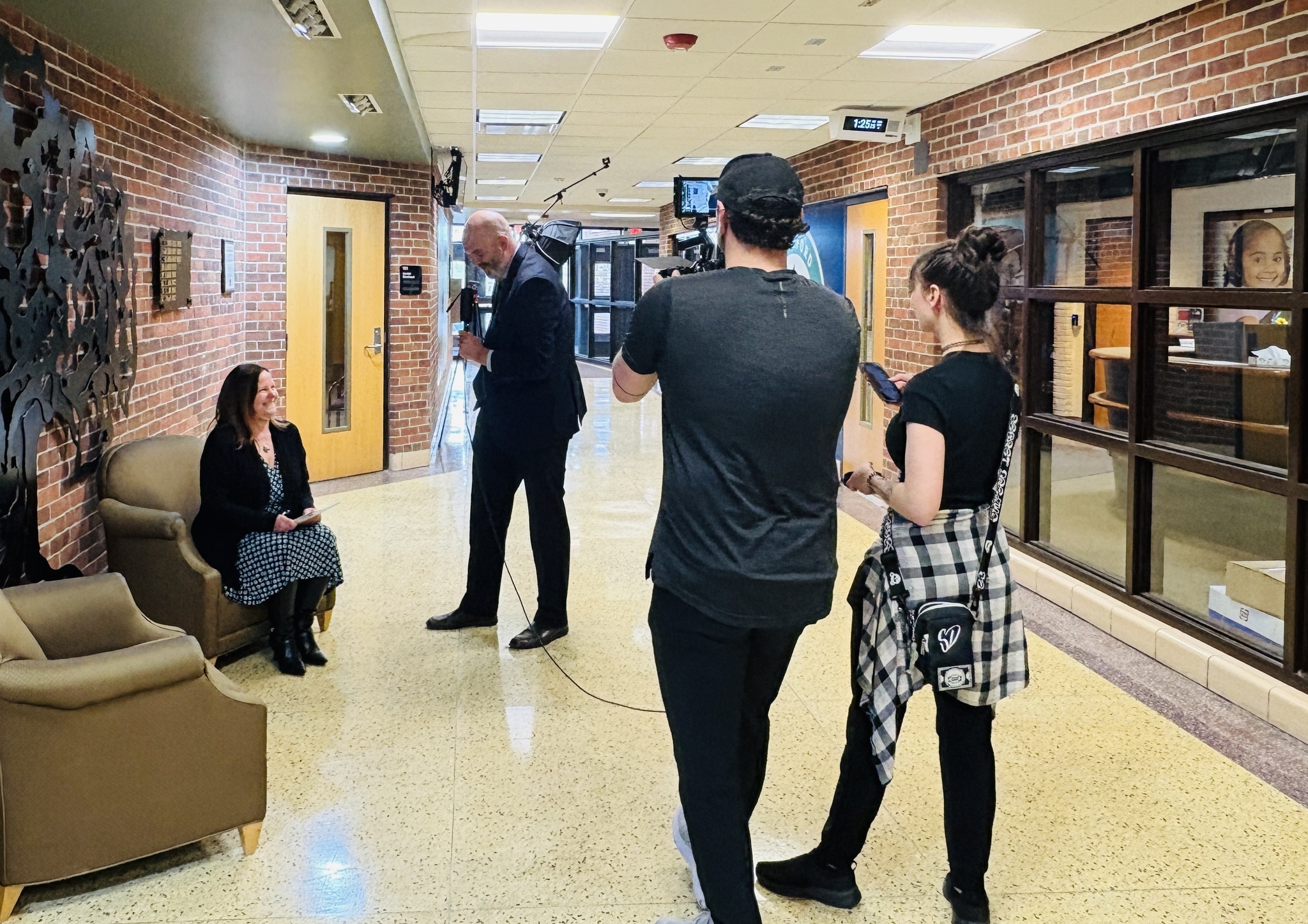 Superintendent Adam Martin Interviews a staff member in a school hallway while a film crew records